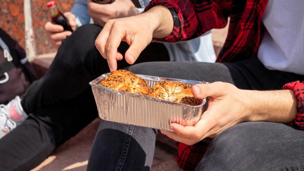 Dos jóvenes amigos sentados en las escaleras de un parque y comiendo