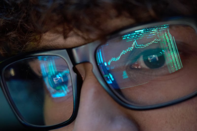 Joven mirando gráficos con lentes en una computadora.