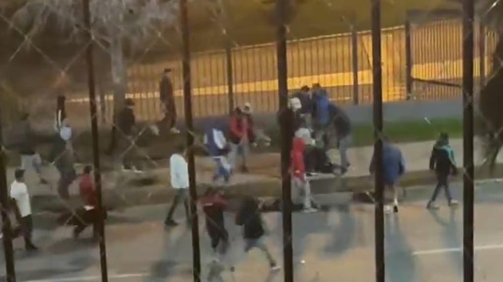 Lo que se supone sería un partido amistoso entre Colo Colo y el equipo Universitario de Perú, terminó con un hincha albo asesinado en las inmediaciones del estadio Monumental, en la comuna de Macul. Crimen que quedó registrado en un video que grabó un vecino al recinto deportivo, dando cuenta del cobarde ataque que sufrió la víctima.
“Frente al Mall Florida Center vi como se metieron con un hincha del Colo Colo y lo apuñalaron... lamentablemente falleció. ASQUEROSO TODO. ¿Por qué nadie menciona lo que hacen esos delincuentes?????”, escribió junto al fatal registro.
En las imágenes se ve arrancando de una decenas de sujetos que corren detrás de él. Uno de ello logra agarrarlo del polerón y lo hace caer al suelo. Ahí, comienzan a golpearlo entre varios y se ve a un individuo que le da un golpe, pero sale del lugar rápidamente.
Todo esto, ocurrió antes del partido, a eso de las 20 horas en avenida Mirador Azul a la altura del 6200. Tras el ataque, donde también habría quedado con heridas de arma blanca, intenta ponerse de pie y escapar de la violenta escena, pero nuevamente es agredido, quedando sin polera.