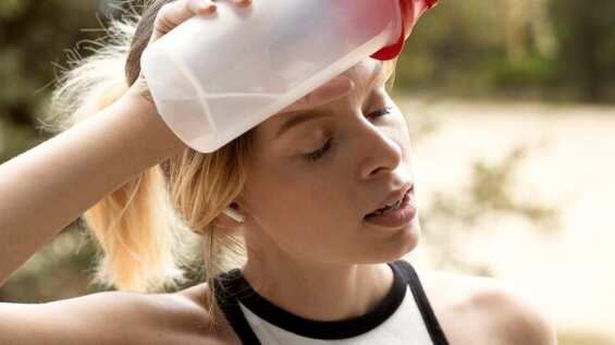 Mujer cansada de tiro medio con botella de agua.