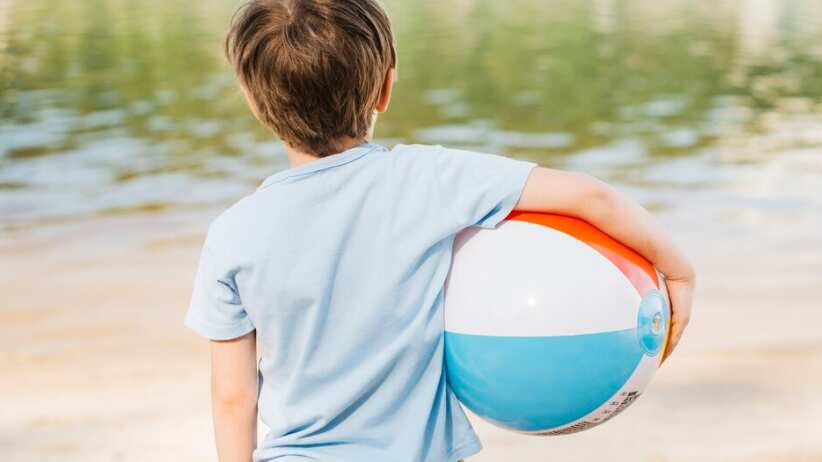 Niño con bola de viento mirando el agua