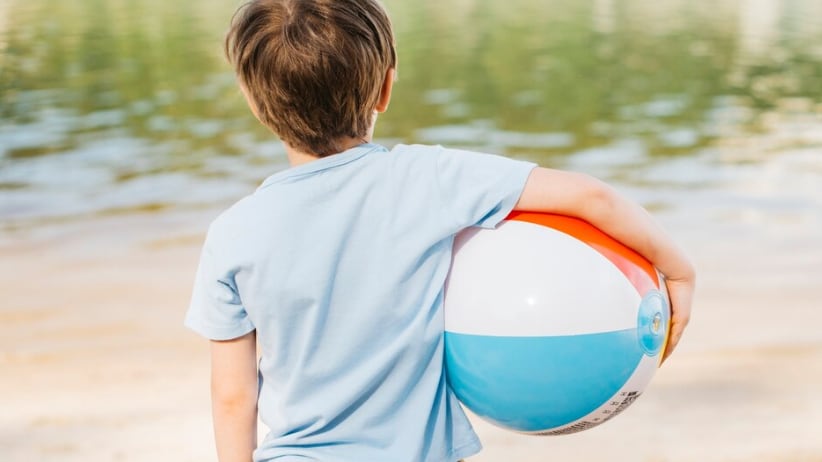 Niño con bola de viento mirando el agua
