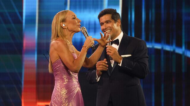 A las 21:22 minutos Karen Doggenweiler hizo su aparición triunfal sobre el escenario de la Quinta Vergara como la flamante animadora del Festival de Viña del Mar 2025.
Y como un hecho inédito en la historia de las 64 ediciones del certamen, fue una mujer quien presentó a su compañero. En este caso, un viejo conocido del festival, su dupla Rafael Araneda.
“Por primera vez en 64 años una mujer le da el puntapie inicial a este festival, estoy emocionada. Estamos listos para vivir seis noches mágicas", confesó, ante la ovación de los presentes.
“No voy a estar sola, me va a acompañar un amigo entrañable, un amigo de años”, dijo presentando al animador, también animó Viña los años 2011 y 2018.
Ahí, de un elegante smoking y humitas apareció el “tío conductor”, con su energía y voz característica.
Además, realizaron unos movimientos de baile hasta instalarse frente al escenario, momento cuando el público les pidió el tradicional piquito.
Araneda pidió permiso de manera simbólica a su esposa Marcela Vacarezza quien estaba en las primeras filas junto a Cristián Sánchez, mientras que Karen bromeó que en este festival iba a ser “la más besada”, puesto que compartirá escenario con José Antonio Neme, Rodrigo Sepúlveda y Francisco Melo.
Eso sí, Araneda prefirió guardar silencio al respecto, puesto que si ocupara la misma lógica, también tendría que darse piquitos con Tita Ureta y la actriz Pola Volpato.