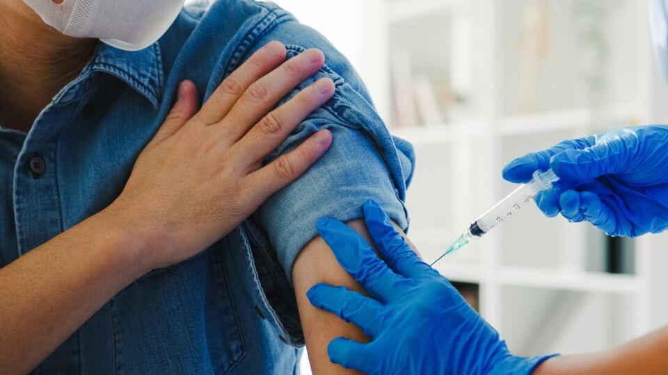 Joven enfermera asiática dando Covid-19 o vacuna antivirus contra la gripe inyectada a un paciente masculino mayor