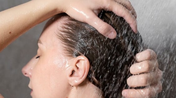 Mujer joven que aplica un producto anticaspa