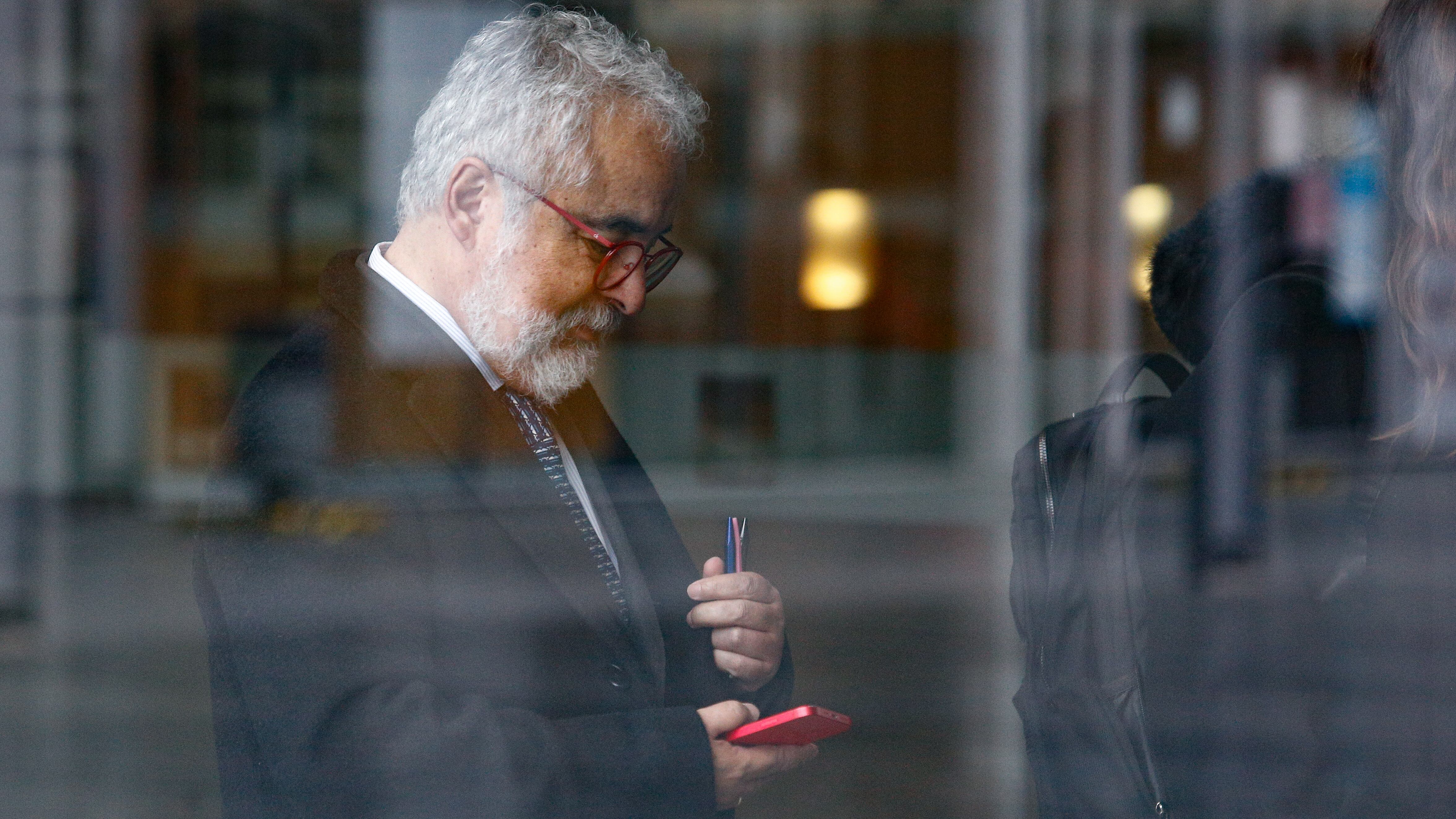 Luis Hermosilla mira mensajes en su (nuevo) celular antes de una audiencia. / AGENCIAUNO