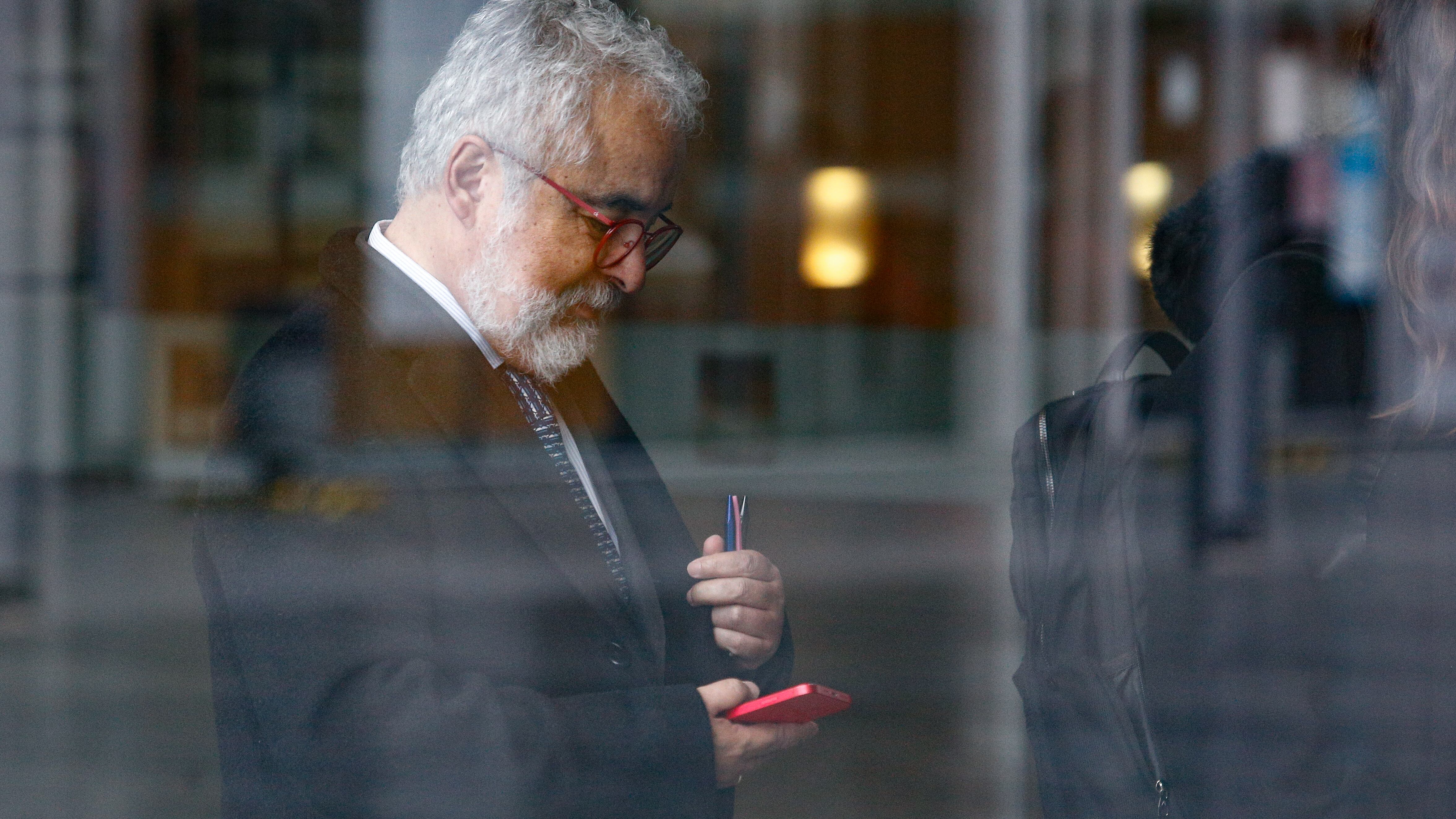 Luis Hermosilla mira mensajes en su (nuevo) celular antes de una audiencia. / AGENCIAUNO