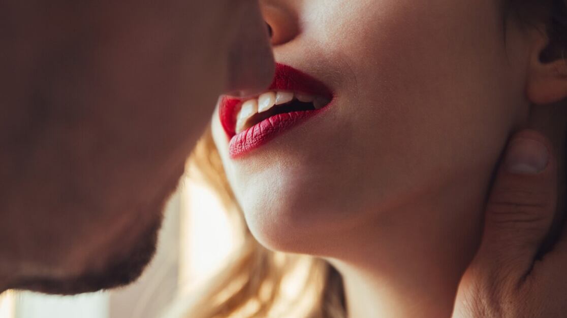 Foto recortada de jóvenes amantes besándose cerca de la ventana en casa.