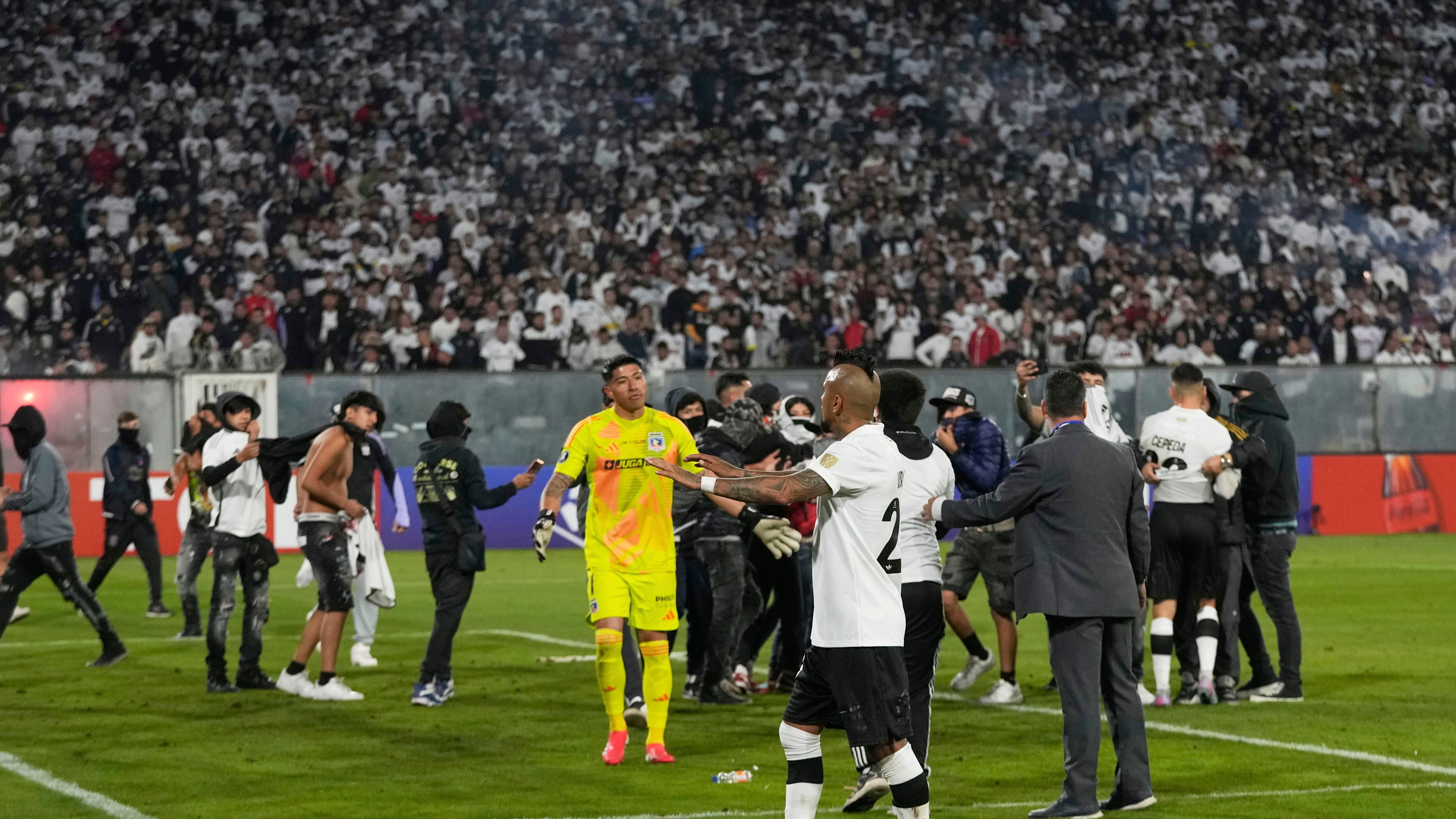 Arturo Vidal of Chile's Colo Colo talks to fans who invaded the field during a Copa Libertadores Group E soccer match between Chile's Colo Colo and Brazil's Fortaleza at the Monumental stadium in Santiago, Chile, Thursday, April 10, 2025. (AP Photo/Esteban Felix)