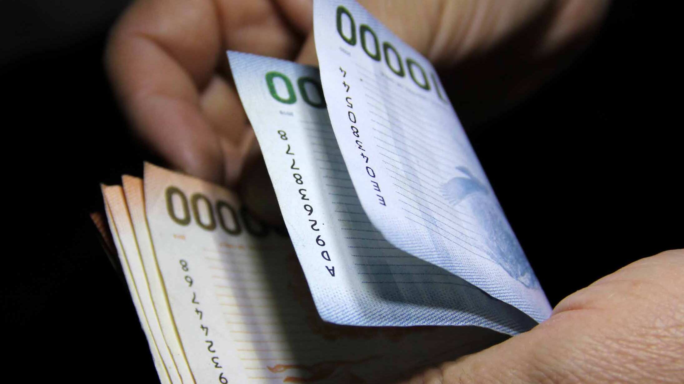 Imagen referencial de un fajo de billetes de $10 mil y 20 mil pesos chilenos.