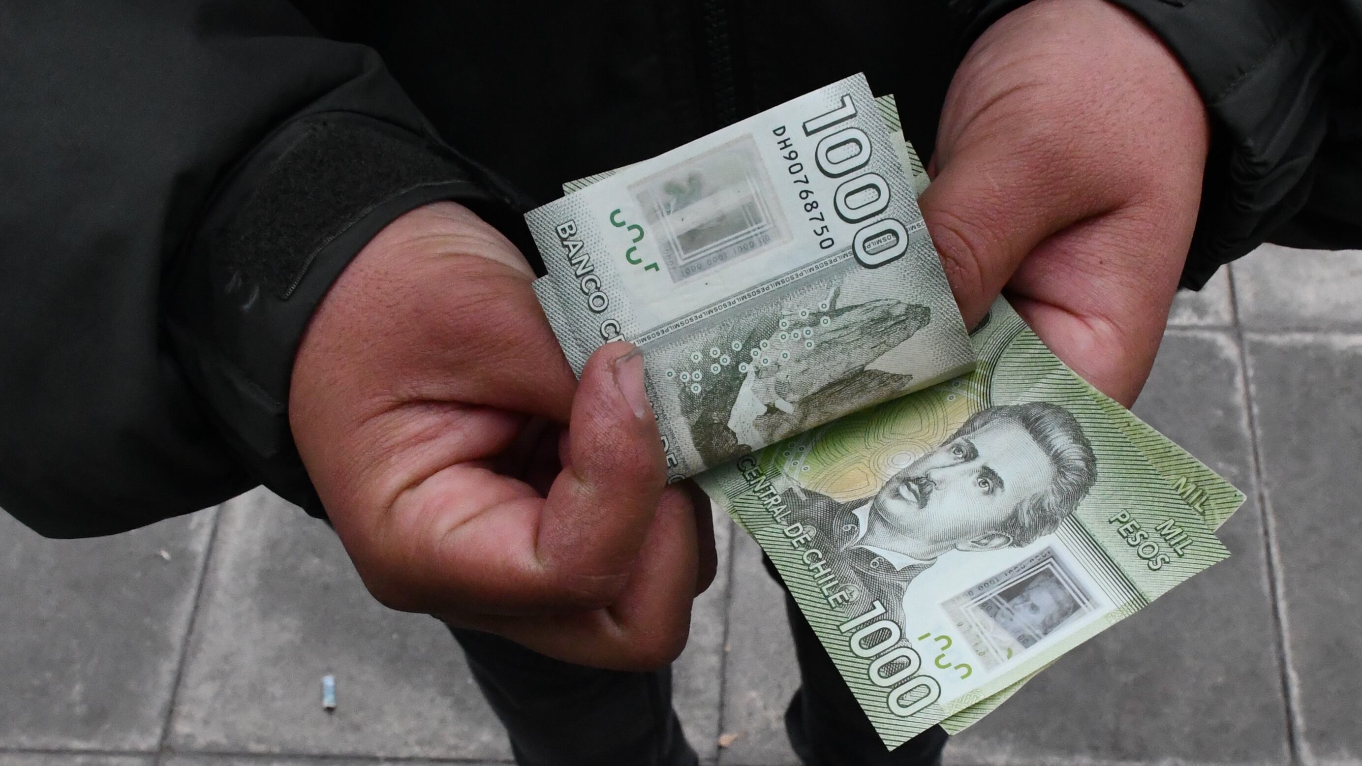 Imagen referencial de un sujeto contando billetes de mil pesos.
