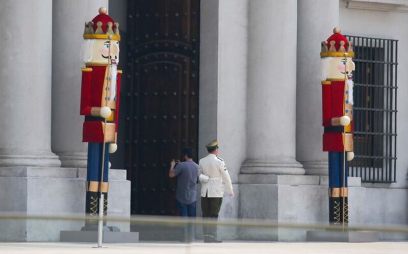 La Moneda se suma a al ambiente navideño que recorre el mundo entero. Si el tradicional arbolito de Navidad no fuera suficiente, en el Palacio de Gobierno quisieron llevar las cosas al siguiente nivel instalando a una “nueva guardia de palacio”.
Se trata de, concretamente, dos enormes soldaditos al estilo más puro del libro El Cascanueces y el rey de los ratones de Ernst Theodor Amadeus Hoffmann. De esta manera, la navideña ornamentación fue ubicada en las puertas de La Moneda que dan hacia La Alameda.
