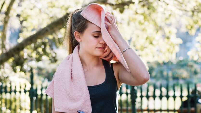 Deportiva mujer limpiando la cara con una toalla