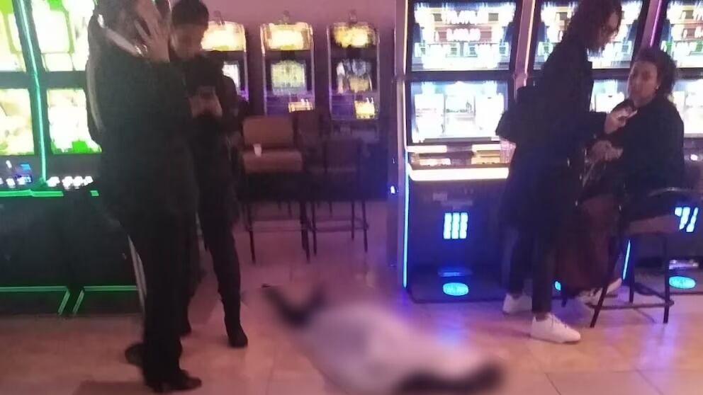 Una mujer de 72 años murió al interior de un casino de juegos en Argentina y quedó tendida en el suelo, mientras los demás concurrentes continuaban apostando en las máquinas tragamonedas.
El hecho ocurrió el pasado viernes en la ciudad Mar del Plata, en el recinto “Bingo Puerto”, ubicado en avenida Edison, en la zona del Puerto.
La mujer se desvaneció y quedó tumbada boca abajo. Fue asistida por personal de seguridad, pero ya se encontraba sin signos vitales.
Luego de la tragedia, los encargados taparon a la adulta mayor con una lona blanca, pero mantuvieron el lugar abierto al público.
Posteriormente llegó personal médico, quienes confirmaron el repentino deceso, confirmando que se trató de una muerte natural. La hija de la mujer llegó al recinto y quedó junto a ella hasta que el cuerpo fue retirado tras los peritajes.
Todo esto ocurrió mientras el casino seguía funcionando y los jugadores apostaban con total normalidad, a solo metros de la mujer fallecida. Situación que fue registrada en un video que se viralizó en redes sociales.