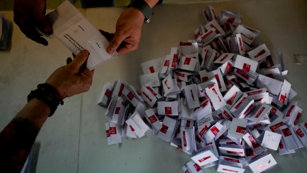 Trabajadores electorales abren los votos para el conteo tras el cierre de urnas en Santiago, Chile, el domingo 17 de diciembre de 2023. Por segunda vez, los chilenos van a un referéndum para decidir si reemplazan la constitución vigente, heredada de la dictadura de Augusto Pinochet, por un nuevo texto. (AP Foto/Esteban Félix)