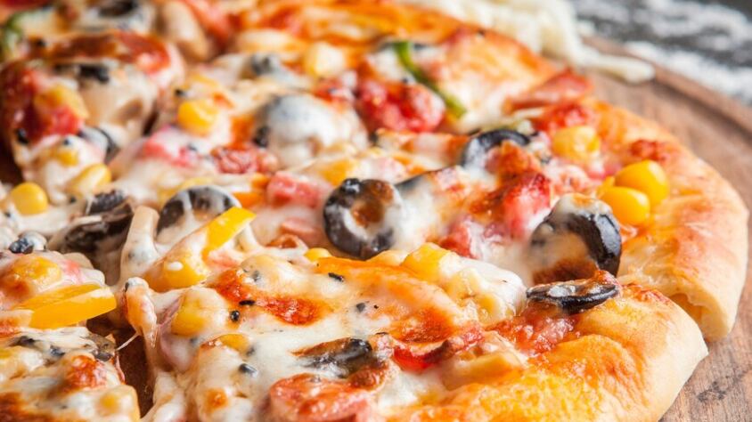 Vista lateral de pizza con pimiento picado en utensilios de cocina