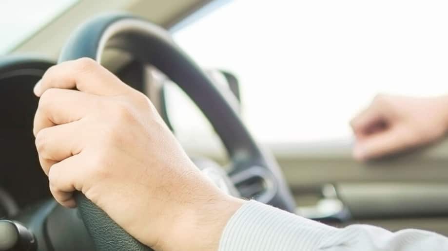 Cerca de un hombre conduciendo un coche con una mano, comportamiento peligroso