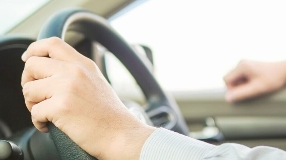 Cerca de un hombre conduciendo un coche con una mano, comportamiento peligroso