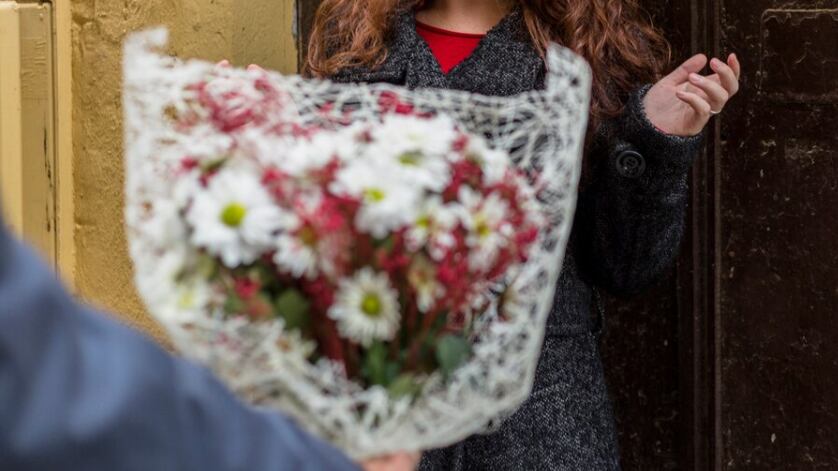 Hombre dando flores a mujer en calle.