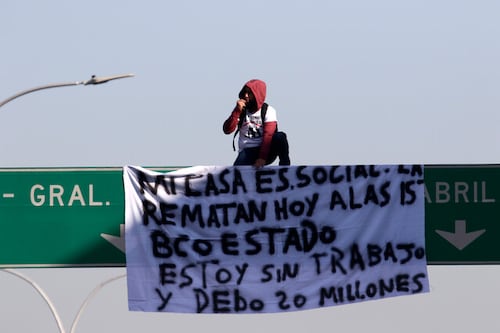 Hombre sube a letrero vial en Santiago a protestar por el remate de su casa