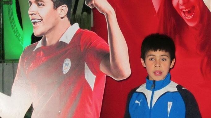 Un pequeño Alexander Aravena posando junto a una figura de Alexis Sánchez