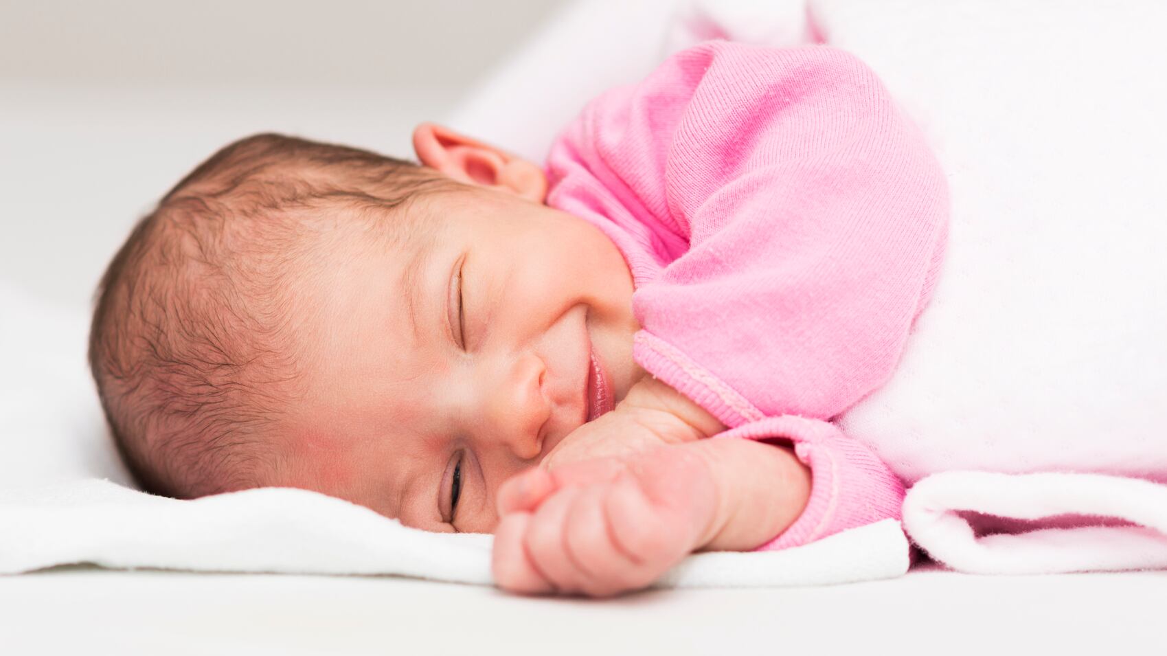 Retrato de una niña recién nacida mientras duerme y sonríe