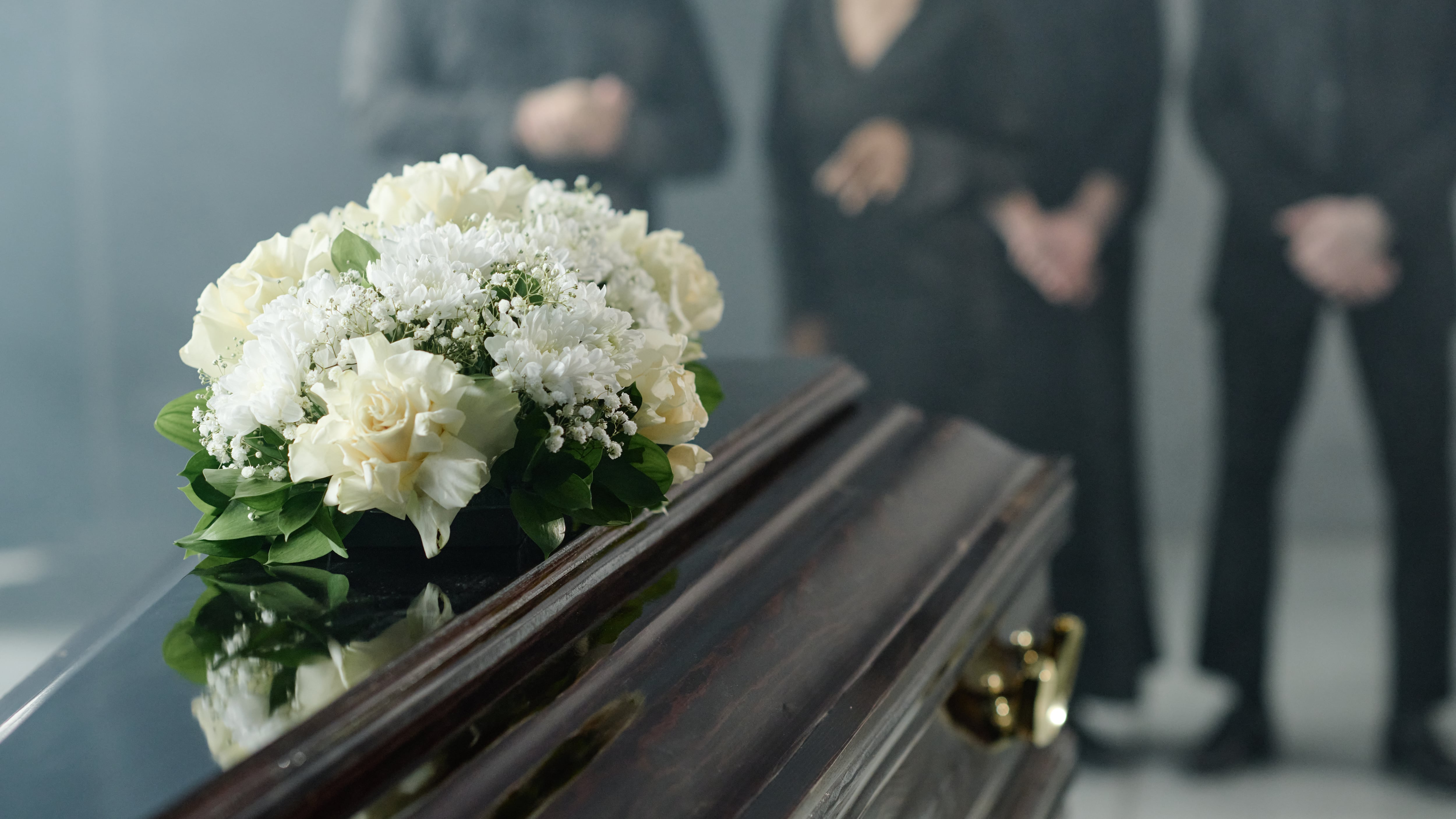 Grupo de personas de mediana edad de luto junto a un ataúd durante la ceremonia fúnebre