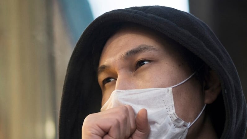 Vista lateral del hombre tosiendo con una máscara médica