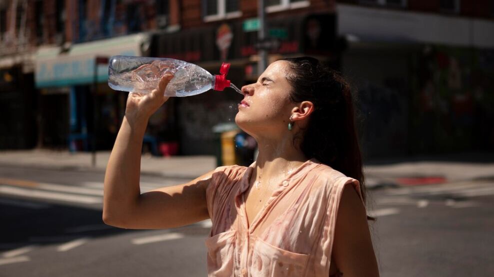 Mujer joven tolerando la ola de calor con una bebida fría